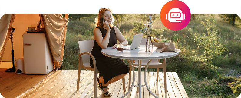 A woman sitting at an outdoor table by a camper van, enjoying the sunlight and browsing through examples of Interactive Voice Response systems.